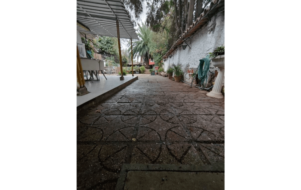 Patio con piso decorado, toldo y jardín con palmera, casa colonial en La Cisterna