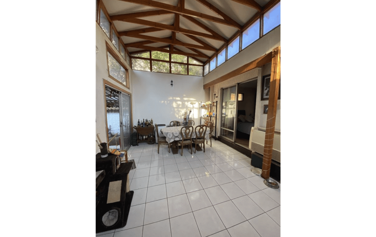 Comedor de invierno techado con vigas de madera vista, casa colonial en La Cisterna