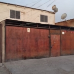 Fachada de la casa de dos pisos con portón metálico, Alto Hospicio