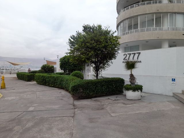 Entrada del Edificio Punta Cavancha con jardines y vista al mar de fondo, Iquique
