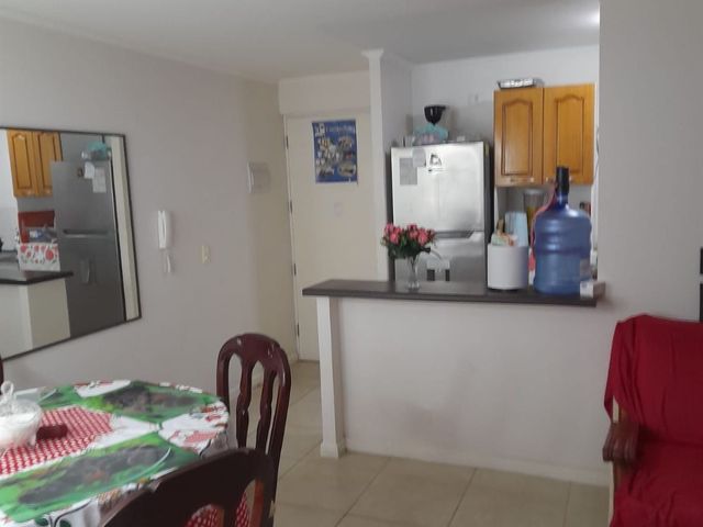 Comedor con vista a la cocina americana y muebles de madera, departamento en Condominio Nuevo Barrio, Iquique