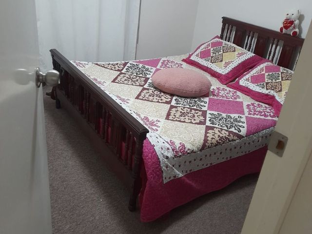 Dormitorio con cama matrimonial de madera, departamento en Condominio Nuevo Barrio, Iquique