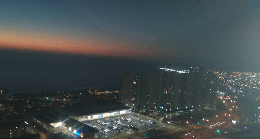 Vista nocturna desde altura hacia supermercado y ciudad, departamento Puesta de Sol, Iquique