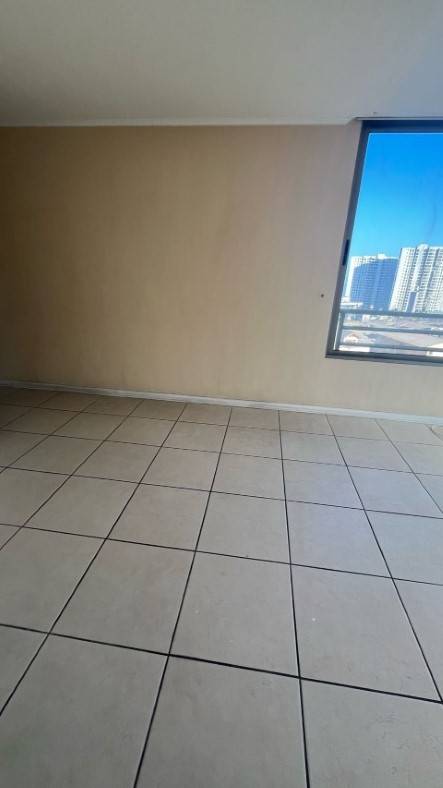 Dormitorio vacío con ventana y vista a edificios y el mar, departamento Puesta de Sol