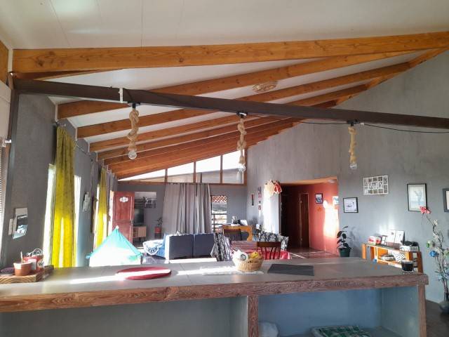 Living con mesón y techo de vigas de madera, parcela con casa en Altos de Miraflores, Pica