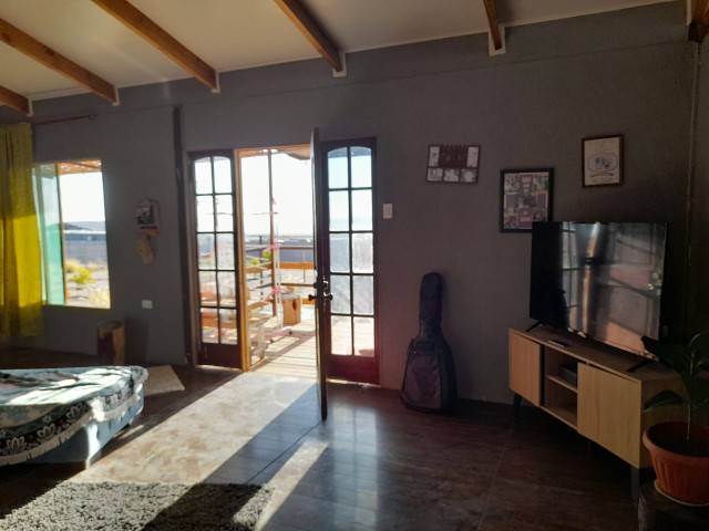 Living con TV y puerta hacia la terraza, parcela con casa en Altos de Miraflores, Pica