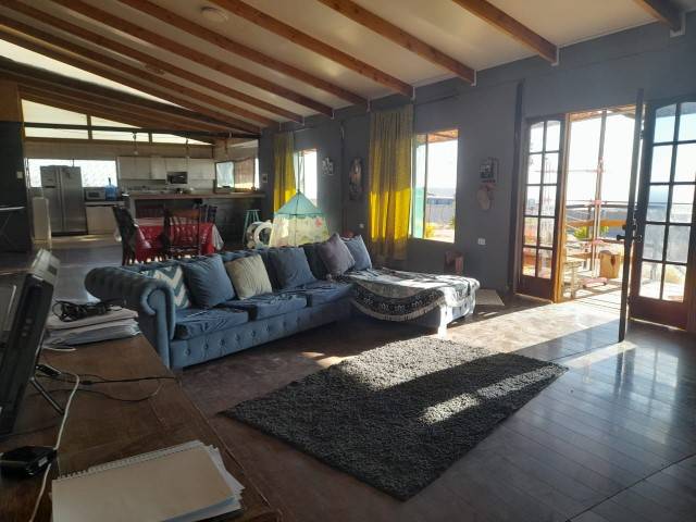 Living con sofá azul y puertas de vidrio hacia la terraza, parcela en Altos de Miraflores, Pica