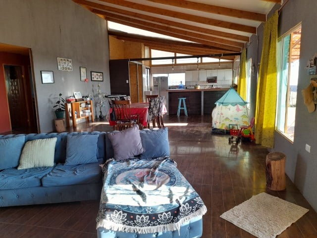 Living amplio con techo de vigas de madera y sofá azul, parcela en Altos de Miraflores, Pica