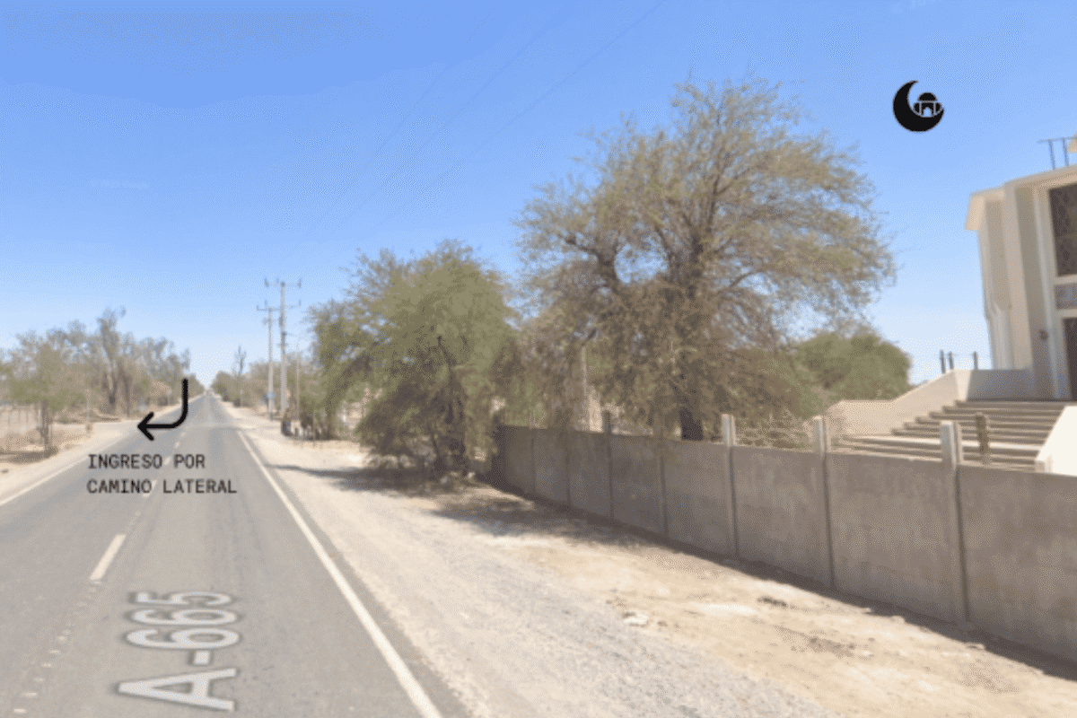 Camino A-665 junto al muro de la Mezquita de La Tirana, con indicación de ingreso lateral al terreno, Pozo Almonte