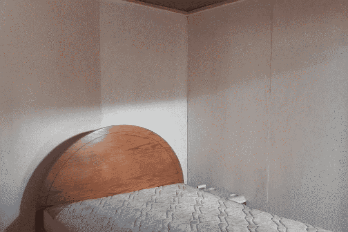 Dormitorio de la cabaña con cama y respaldo de madera, requiere mejoras, parcela en La Tirana, Pozo Almonte