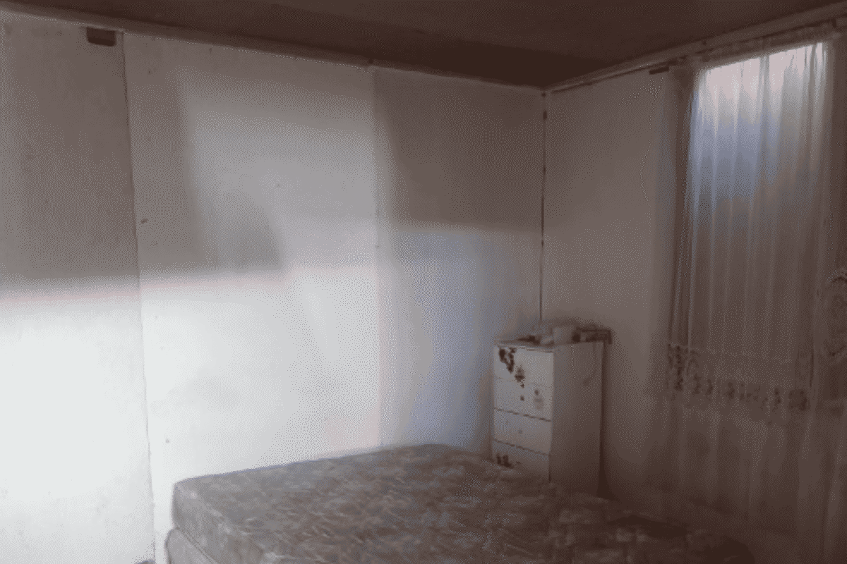 Dormitorio de la cabaña con cómoda y ventana con cortina, requiere mejoras, parcela en La Tirana, Pozo Almonte