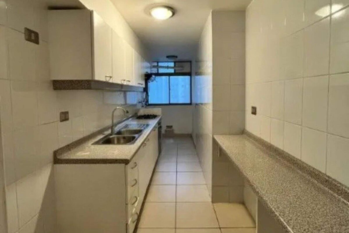 Cocina en línea con muebles blancos, departamento con vista al mar en Iquique