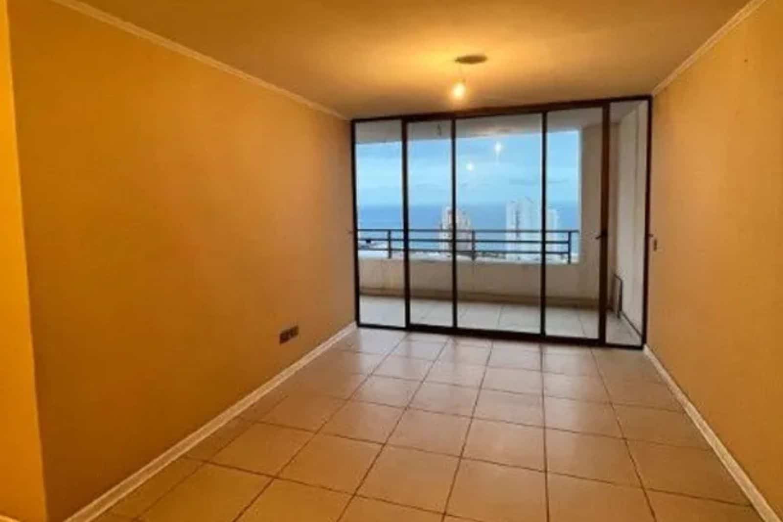 Living vacío con ventanal y vista al mar, departamento en Iquique