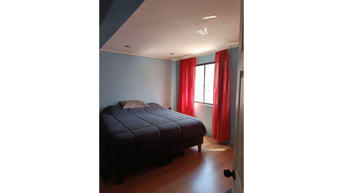 Dormitorio con cama matrimonial y cortinas rojas, casa en venta en Alto Hospicio