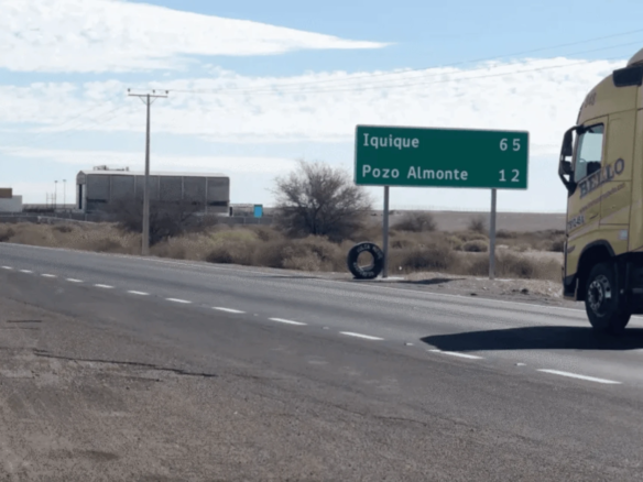 Señal de ruta indicando distancias a Iquique y Pozo Almonte, terreno industrial en Pozo Almonte