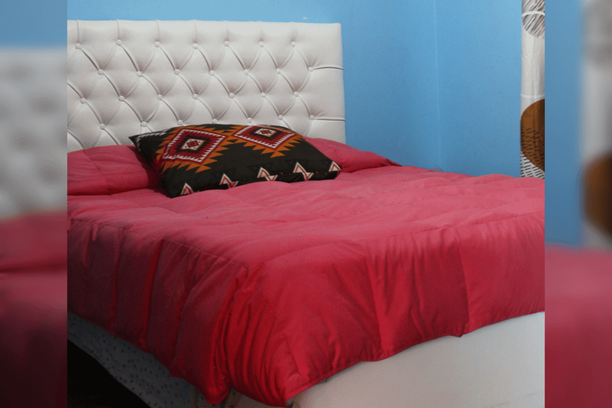 Dormitorio con cama y cubrecama rojo, parcela con 3 casas en La Tirana, Pozo Almonte