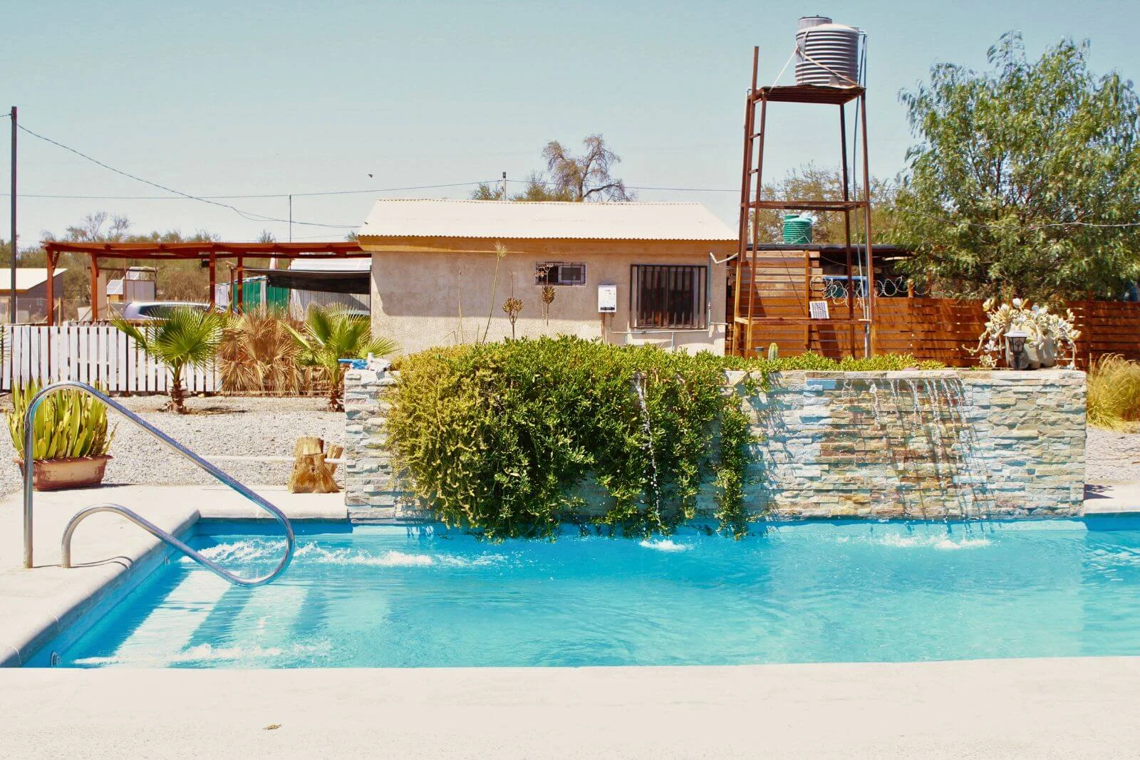 Piscina con muro de piedra decorativo y cascada, parcela con 3 casas en La Tirana, Pozo Almonte