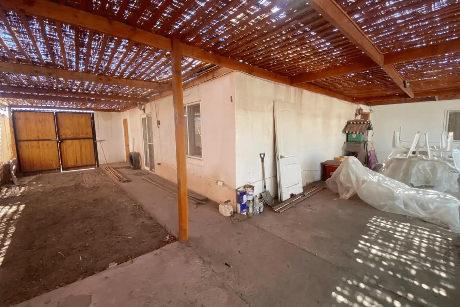 Cobertizo techado lateral con puerta de bodega y materiales de construcción