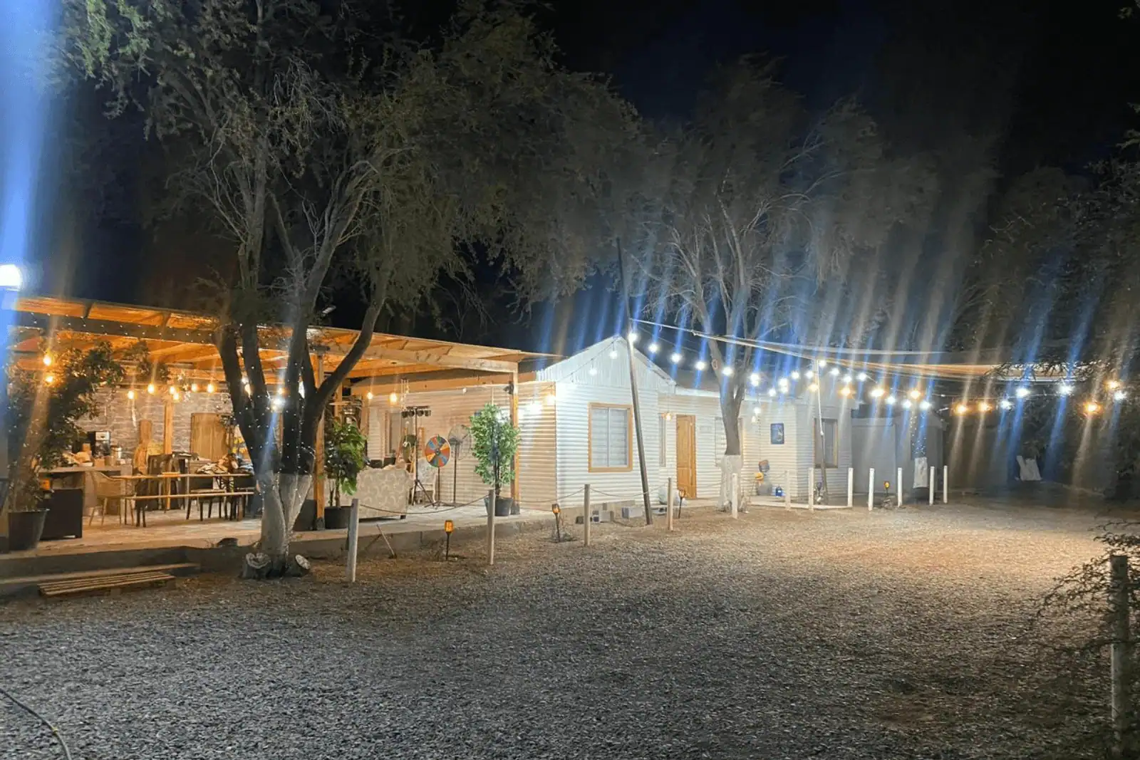 Vista nocturna de la cabaña principal iluminada con guirnaldas de luces, parcela en La Huayca, Pozo Almonte