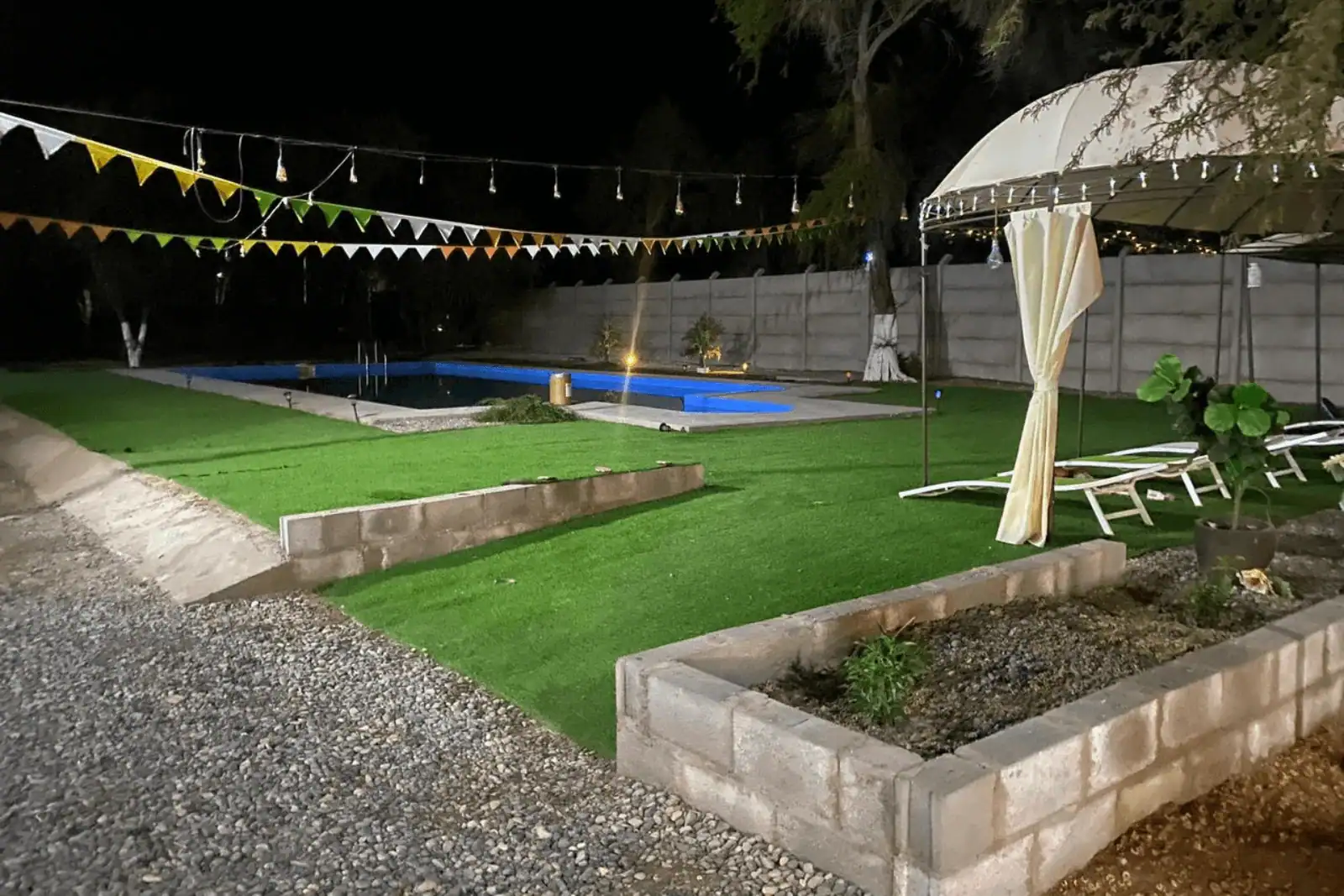 Piscina iluminada de noche con pasto sintético y quincho, parcela en La Huayca, Pozo Almonte