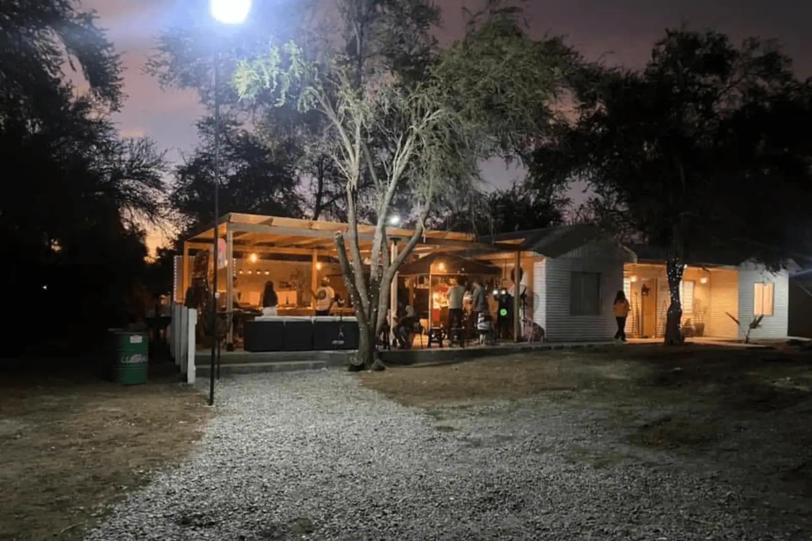 Vista nocturna del quincho iluminado junto a la cabaña principal, parcela en La Huayca, Pozo Almonte