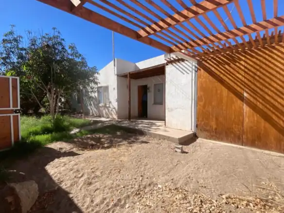 Fachada de casa en venta en Condominio Altos de Pica, con pérgola de madera y patio de tierra