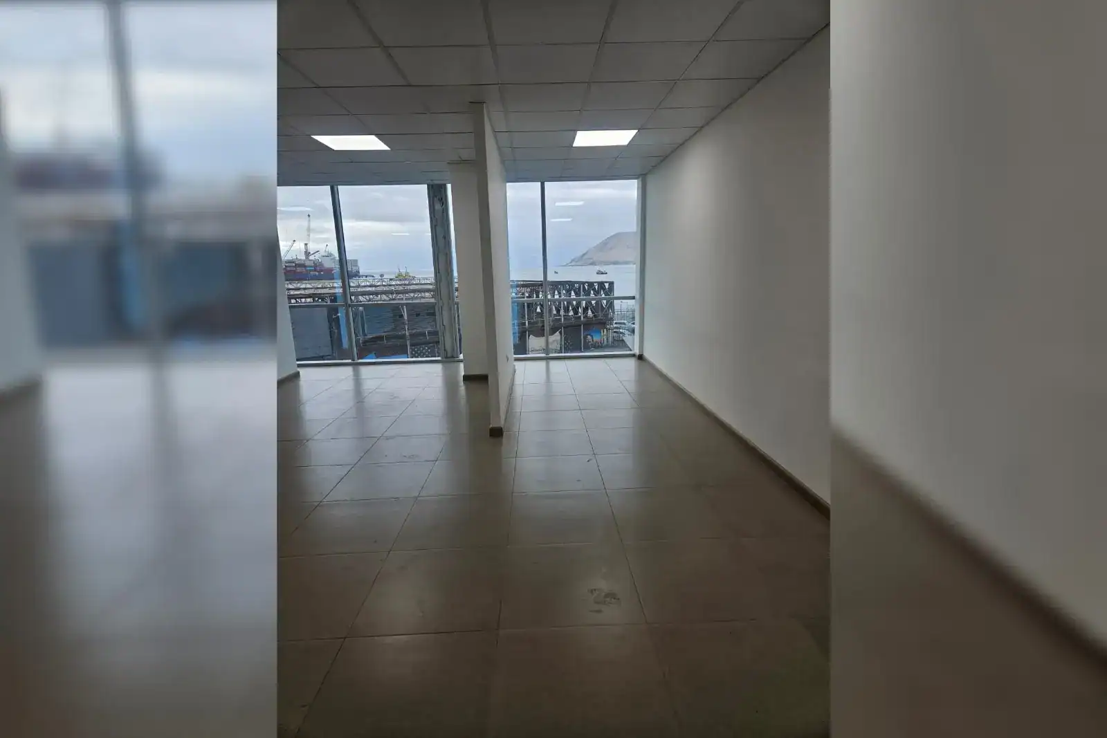 Área de trabajo abierta con ventanales y vista al puerto, oficina en Torre Capital, Iquique
