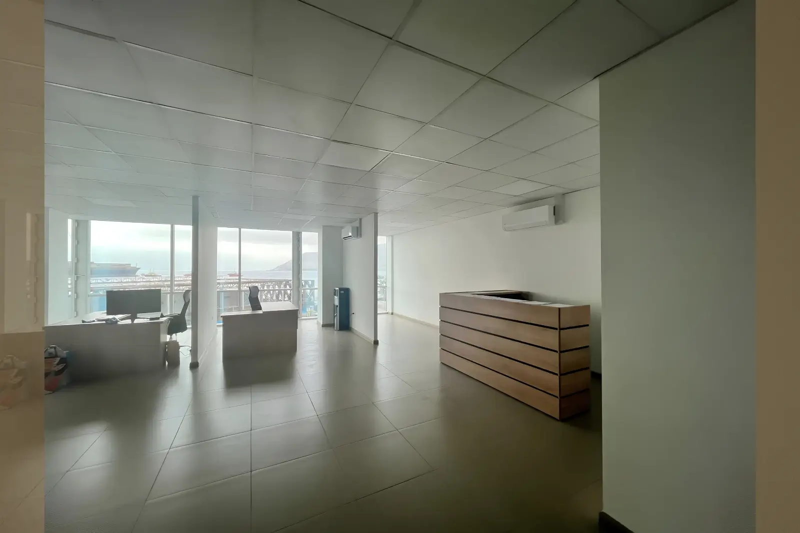 Otra vista de la recepción con mesón de madera y vista al puerto, oficina en Torre Capital, Iquique